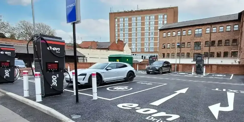 The E.ON Drive EV charging hub off North Street, York. Two E.ON Drive ultra-rapid chargers stand in the foreground, a white electric car is parked on a charging bay marked with the E.ON Drive logo, and brick office buildings line the far side of the car park.